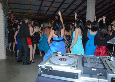 Image of group of people dancing with dj equipment in the foreground